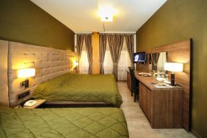 Habitación de hotel con cama verde y escritorio. en Hotel Çarshia e Jupave en Gjakove