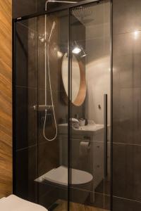 a bathroom with a shower with a sink and a mirror at VacationClub - Spokojna 24E Apartament B1 in Wisła