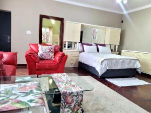 ein Hotelzimmer mit einem Bett und einem roten Stuhl in der Unterkunft City Gate Two in Pietermaritzburg