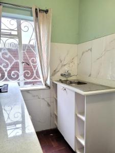 eine kleine Küche mit einem Waschbecken und einem Fenster in der Unterkunft City Gate Two in Pietermaritzburg