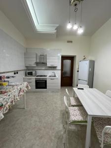 cocina con armarios blancos, mesa y sillas en Barbi’s House, en Nápoles