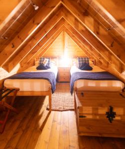 a bedroom with two beds in a wooden attic at Tigh Lachie at Mary's Thatched Cottages, Elgol, Isle of Skye in Elgol
