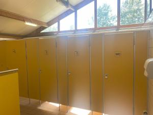 een rij gele kluisjes in een badkamer bij Camping Donkershoeve in Sint-Oedenrode