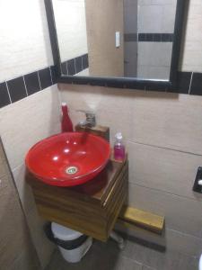 baño con lavabo rojo y espejo en Departamentos mora en Santa Teresita