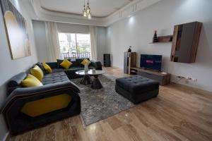 uma sala de estar com um sofá preto e almofadas amarelas em Moderne appart résidence privée em Tânger