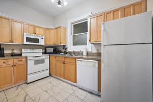 una cocina con electrodomésticos blancos y armarios de madera en Downtown Digs~King Bed~UPSTAIRS Apartment~Downtown Eustis en Eustis