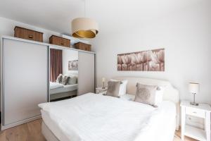 a white bedroom with a large white bed and a mirror at Red Jay Karlin Area Apartment with Garage and Balcony in Prague