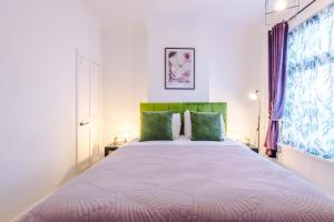 1 dormitorio con 1 cama grande con almohadas verdes en Stylish 3Bed Retreat - Walk to Coventry's Delights en Coventry