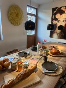 una mesa de madera con pan y comida. en Manoir au Bois, en Braine-le-Château