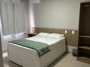ein Schlafzimmer mit einem Bett mit einer grünen Decke darauf in der Unterkunft Mahle Comfort Hotel in Campina Grande do Sul