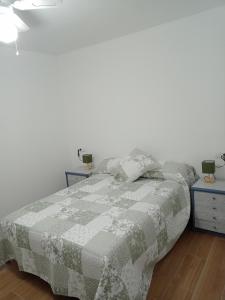 um quarto com uma cama com um cobertor cinzento e branco em Apartamento_Santa Isabel em Utrera