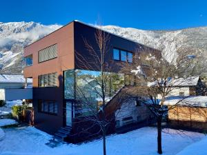 a building in the snow with mountains in the background at Appartement Two in Ötztal-Bahnhof