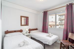 ネルハにあるBahia 49 Apartments Casasolのベッドルーム1室(ベッド2台、窓付)