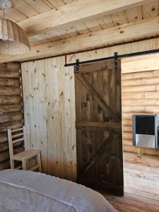 1 dormitorio con pared de madera y puerta de granero en Estadia de campo en San Andrés de Giles