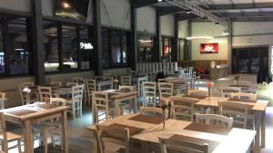 D' Magic في Broşteni: مطعم بطاولات خشبية وكراسي بيضاء