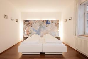 a white room with four beds in front of a painting at Brauereigasthof Krone in Tettnang