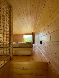 a room with a bed in a wooden room with a window at kiva cabin in Horné Hámre
