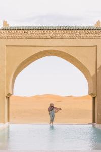 a person standing in the water under a bridge at Sahara pearl Hotel in Merzouga