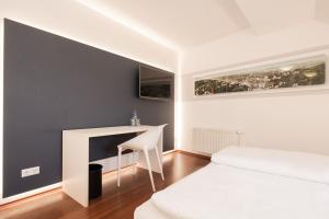 a bedroom with a white bed and a desk at Brauereigasthof Krone in Tettnang