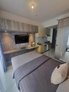 a bedroom with a large bed and a kitchen at Mashley Room Prestige Apartment SKY HOUSE BSD in Cilandak