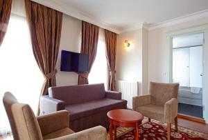 sala de estar con sofá, 2 sillas y TV en Aren Suites, en Estambul