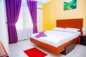 - une chambre avec un grand lit et des rideaux violets dans l'établissement RESIDENCE BELMANN, à Douala