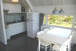 uma cozinha branca com uma mesa e cadeiras brancas em De Vlier 25* em Nieuwvliet
