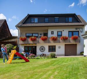 Eine Frau steht vor einem Haus mit Spielplatz in der Unterkunft Ferienwohnung Odenwald in Wald-Michelbach