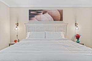 W - Atlanta Luxury 1bdr 1bath ensuite shared Condo in prime location في أتلانتا: غرفة نوم بسرير ابيض مع لوحة على الحائط