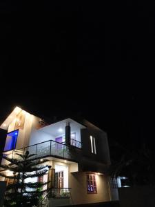 a white building with a balcony at night at Marari Anns Casa Beach Homestay in Mararikulam