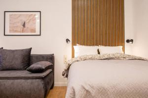 ein Schlafzimmer mit einem Bett und einem Sofa in der Unterkunft Modern Riverside Stays for 4 in Vilnius