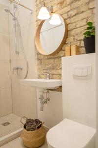ein Badezimmer mit einem Waschbecken, einem Spiegel und einem WC in der Unterkunft Modern Riverside Stays for 4 in Vilnius
