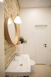 ein Badezimmer mit einem Waschbecken, einem Spiegel und einem WC in der Unterkunft Modern Riverside Stays for 4 in Vilnius