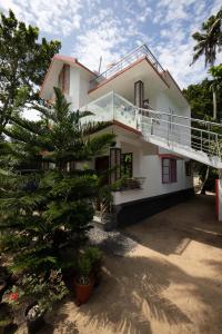 Una casa blanca con un árbol delante. en Marari Anns Casa Beach Homestay, en Mararikulam