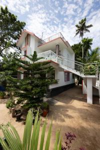 a white house with a palm tree in front of it at Marari Anns Casa Beach Homestay in Mararikulam