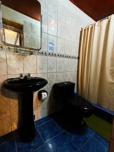a bathroom with a black toilet and a sink at Wayras Hostal in Ollantaytambo