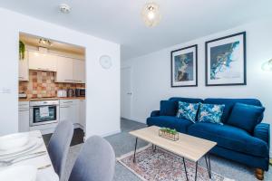 a living room with a blue couch and a table at The Consort Serviced Apartment Coventry in Coventry