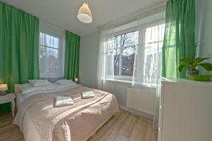 - une chambre avec des rideaux verts, un lit et une fenêtre dans l'établissement VacationClub – Lipowa 1 Apartament 3, à Wisła