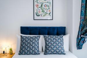 a bedroom with a blue headboard and two pillows at The Consort Serviced Apartment Coventry in Coventry