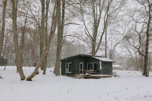 a small black cabin in a snow covered forest at Dunduriņi in Talsi