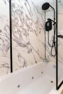 a shower with a black and white marble wall at The Old Deanston Workers Cottage in Doune