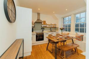 a kitchen with a table and a clock on the wall at The Old Deanston Workers Cottage in Doune