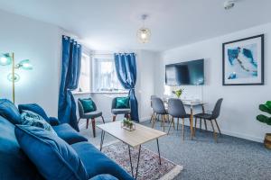 a living room with a blue couch and a table at The Consort Serviced Apartment Coventry in Coventry