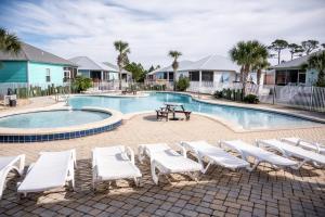 a swimming pool with white lounge chairs and a picnic table at Cottage Beach House Steps From Beach 3 bedroom 2 bath in Gulf Shores