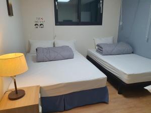 two twin beds in a room with a lamp at 29 Play House in Incheon