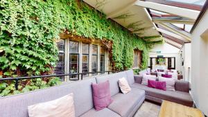 a room with a green wall with couches and pillows at Stirk House Hotel in Clitheroe