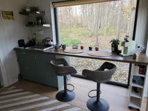 kuchnia z blatem i dwa stołki przed oknem w obiekcie Ozola stāsts atpūtas namiņš 