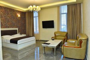 a hotel room with a bed and chairs and a tv at Macao Hotel in Yerevan