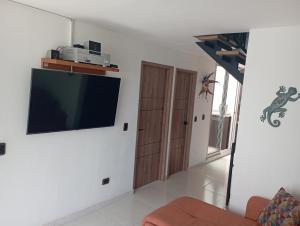 sala de estar con TV de pantalla plana en la pared en Condominio Palma Real, en Granada