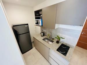 a small kitchen with a refrigerator and a sink at Five Moderno Depto. Ciudad de las Esculturas in Resistencia